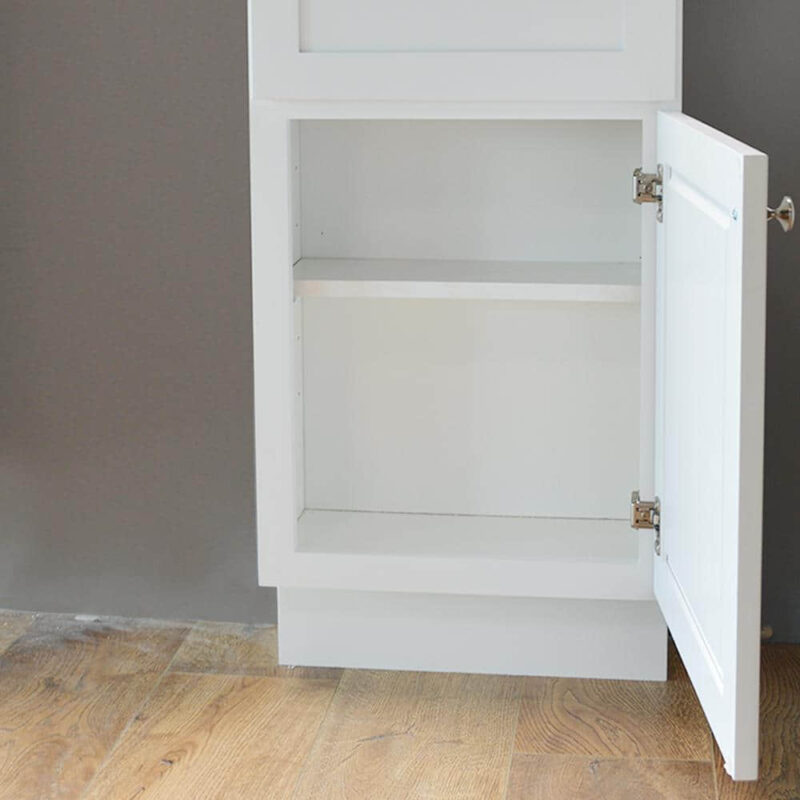 White kitchen cabinet with open door on wooden floor.