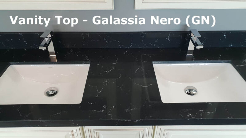 Black vanity top with two sinks and modern faucets.