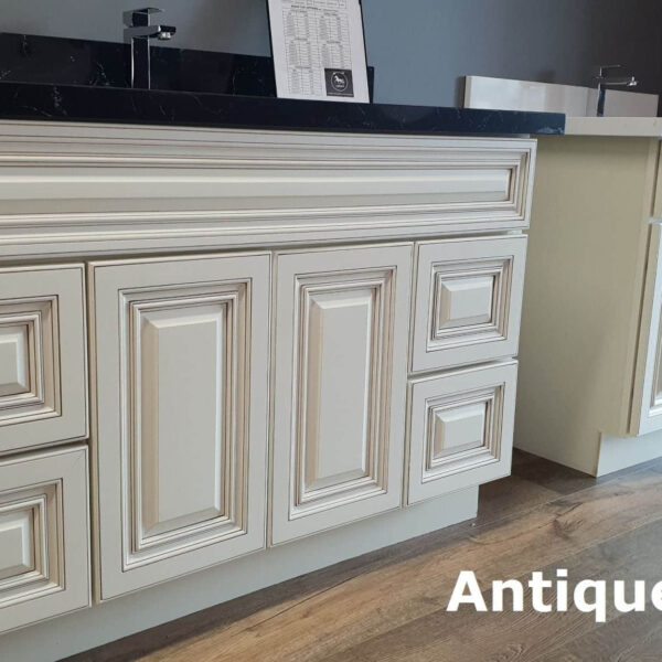 Antique-style kitchen cabinets with intricate detailing and dark countertop.