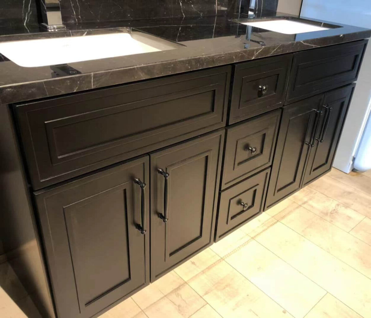 Black kitchen cabinets with marble countertop and dual sinks.