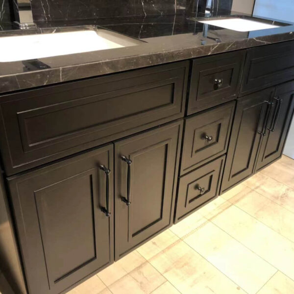 Black kitchen cabinets with marble countertop and dual sinks.