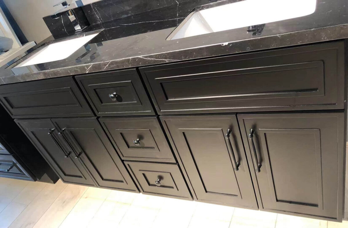 Black kitchen cabinets with marble countertop and dual sinks.