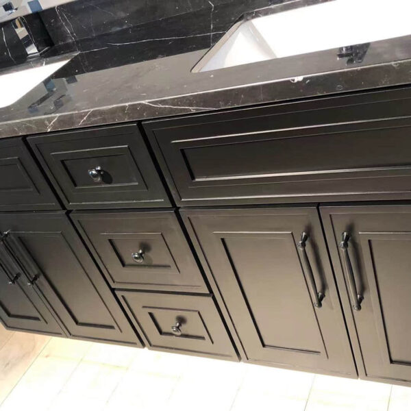 Black kitchen cabinets with marble countertop and dual sinks.
