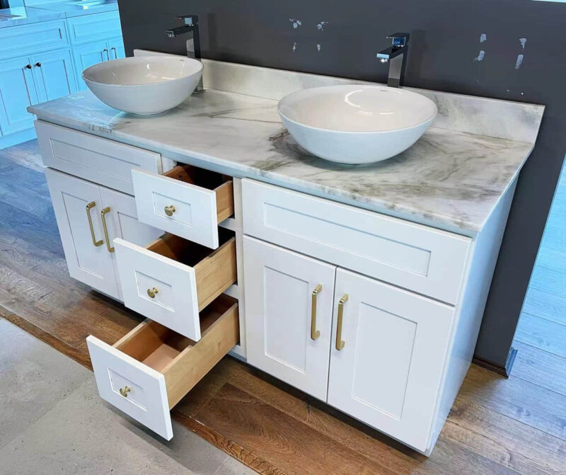 Double sink vanity with open drawers in a modern kitchen showroom.