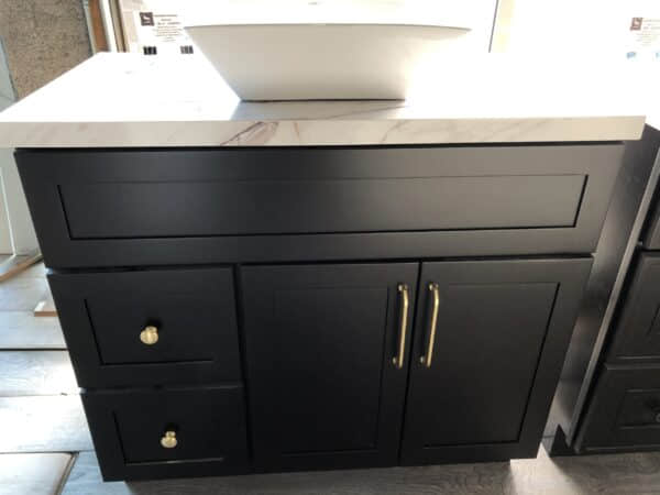 Black kitchen cabinet with marble countertop and white sink.
