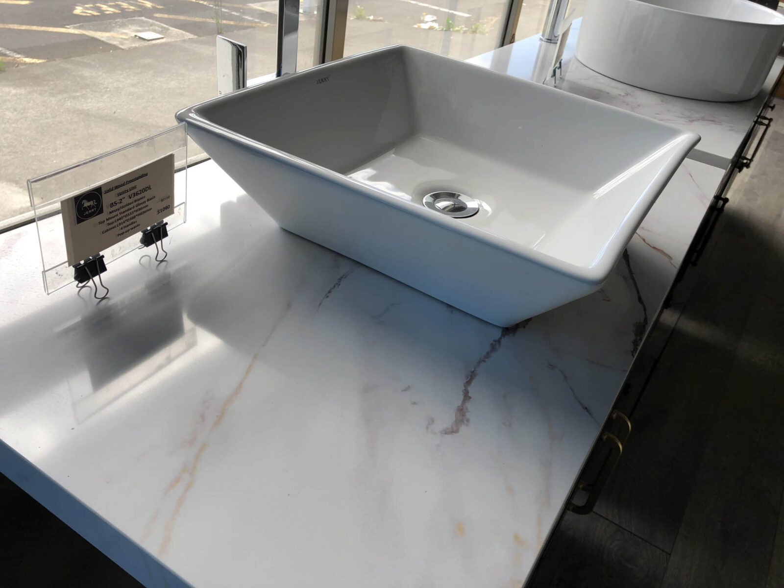 Square white sink on marble countertop in showroom.