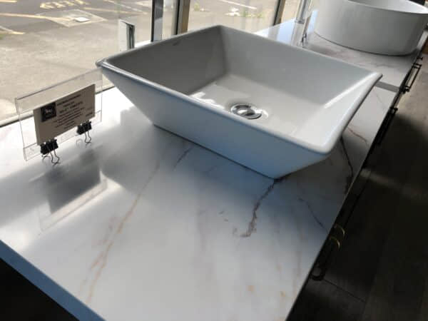 Square white sink on marble countertop in showroom.