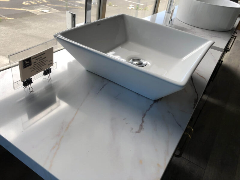 Square white sink on marble countertop in showroom.
