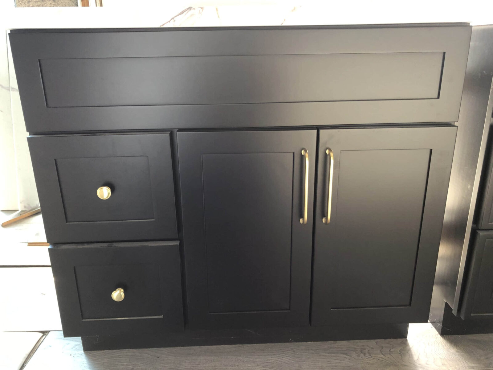 Black kitchen cabinet with gold handles and drawers.