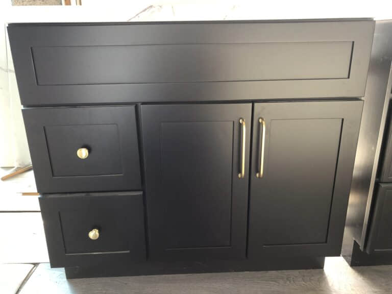 Black kitchen cabinet with gold handles and drawers.