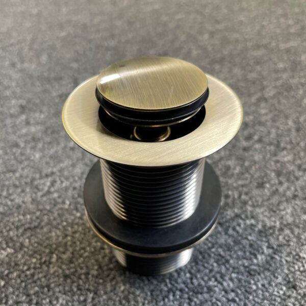 Bronze pop-up waste drain on textured surface.