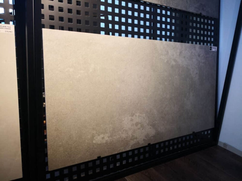 Tile sample displayed on a black grid panel in a showroom.