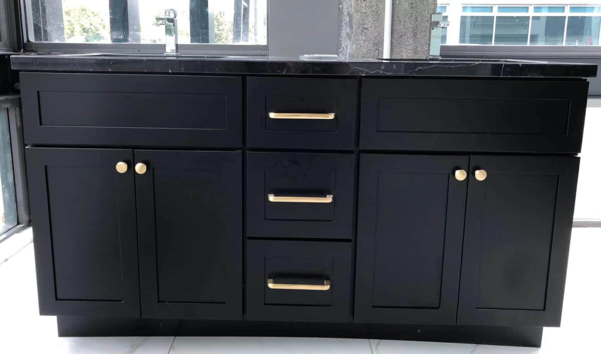 Black marble kitchen cabinet with gold handles in modern setting.