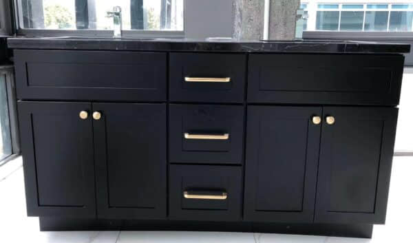Black marble kitchen cabinet with gold handles in modern setting.