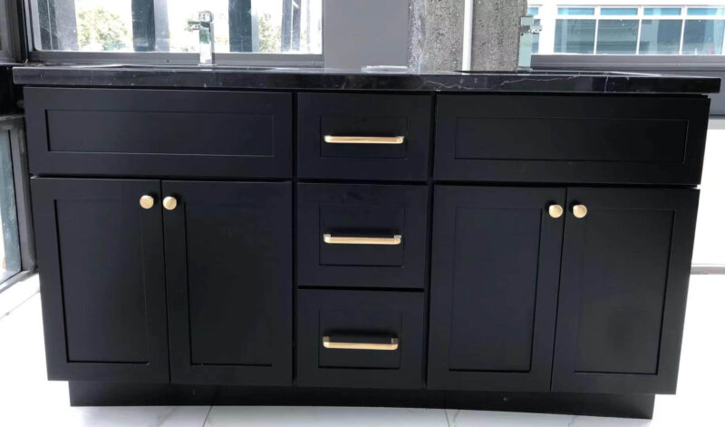 Black marble kitchen cabinet with gold handles in modern setting.