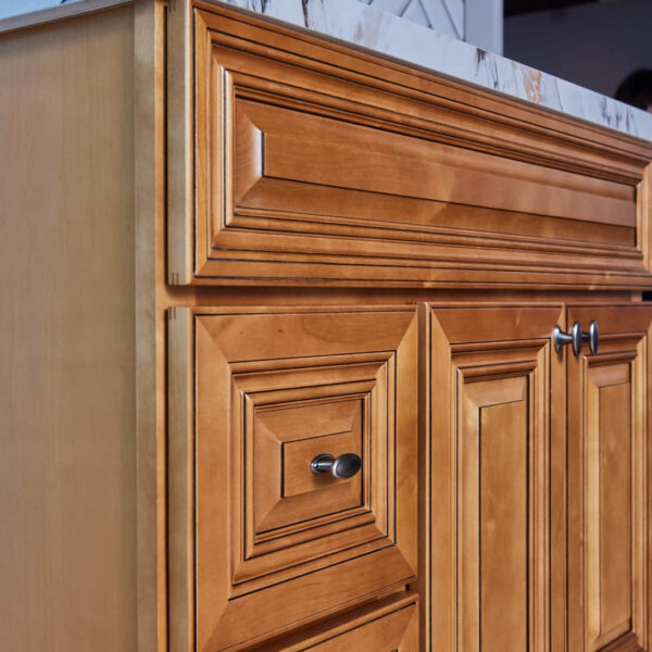 Wooden kitchen cabinet with marble countertop and herringbone tile backsplash.