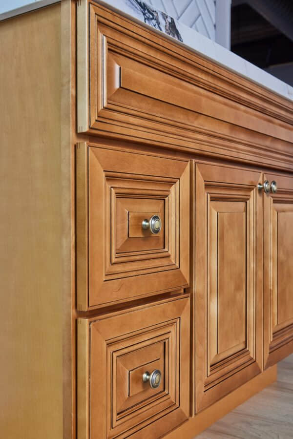 Wooden kitchen cabinet with detailed paneling and metal knobs.