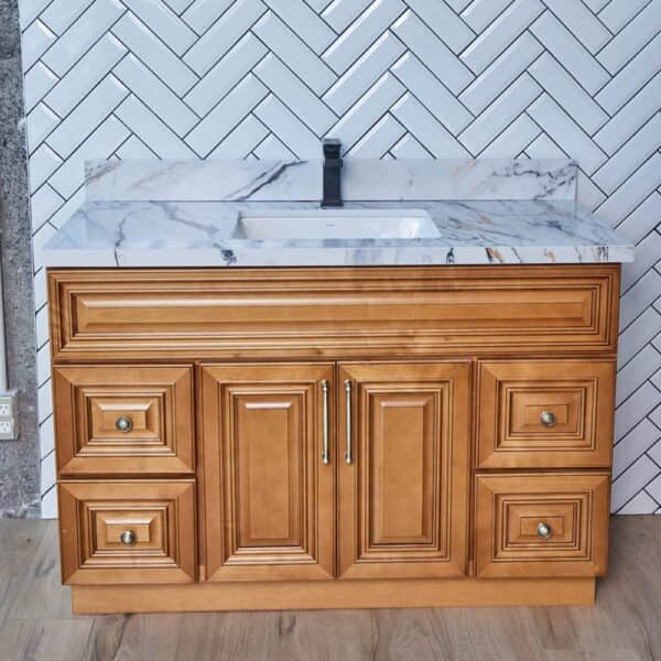 COG-V4720D-1-1.jpg Wooden bathroom vanity with marble countertop against herringbone tile wall.