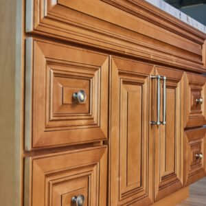 Wooden kitchen cabinet with ornate paneling and metal handles.