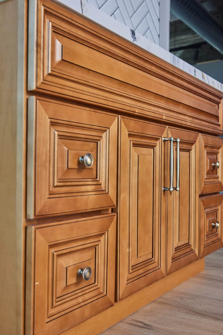 Wooden kitchen cabinet with ornate paneling and metal handles.