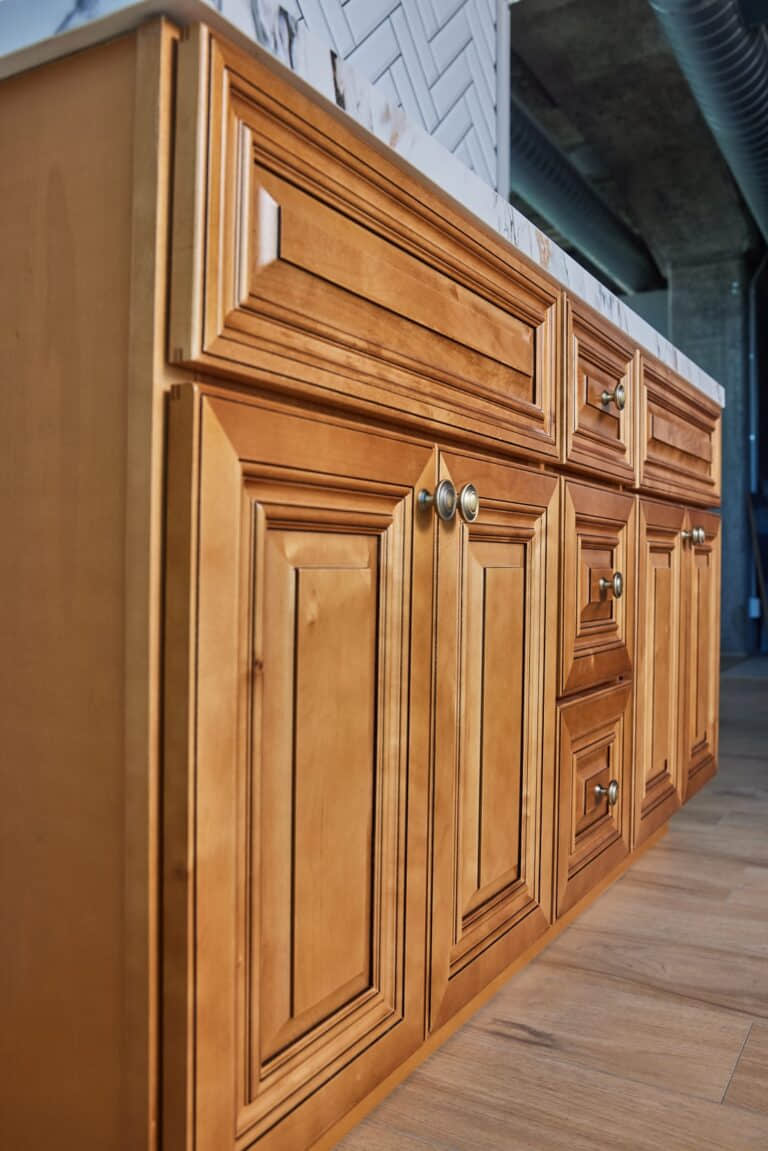 Wooden kitchen cabinets with brass handles in a modern kitchen setting.