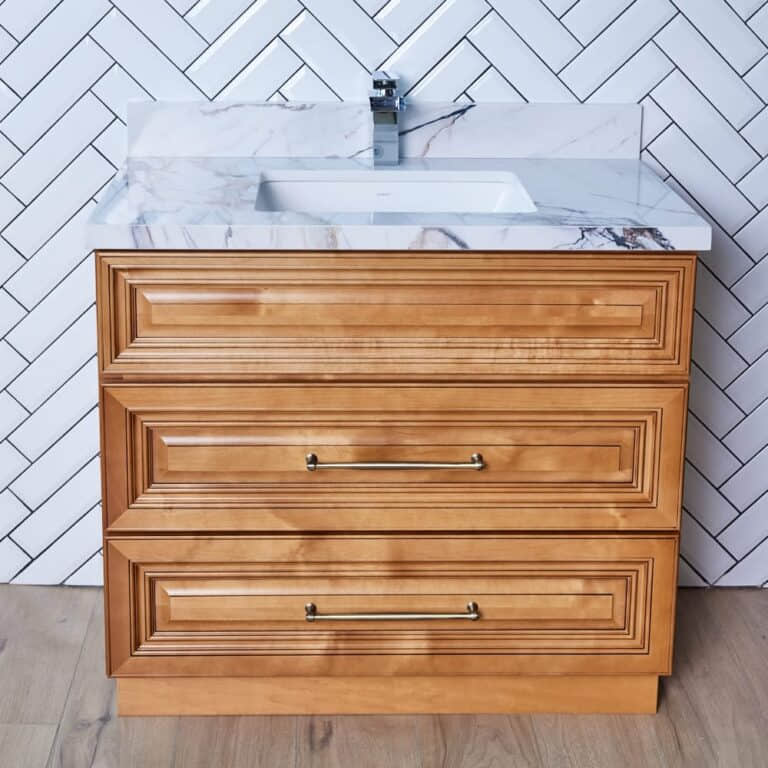 Wooden bathroom vanity with marble countertop and herringbone tile backsplash.
