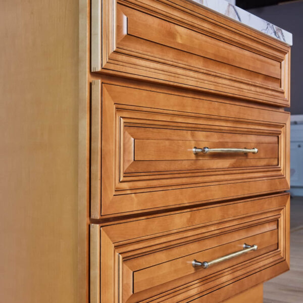 Wooden kitchen cabinet with three drawers and metal handles.