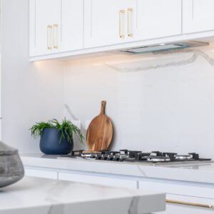 Modern kitchen with white cabinets and marble countertops.