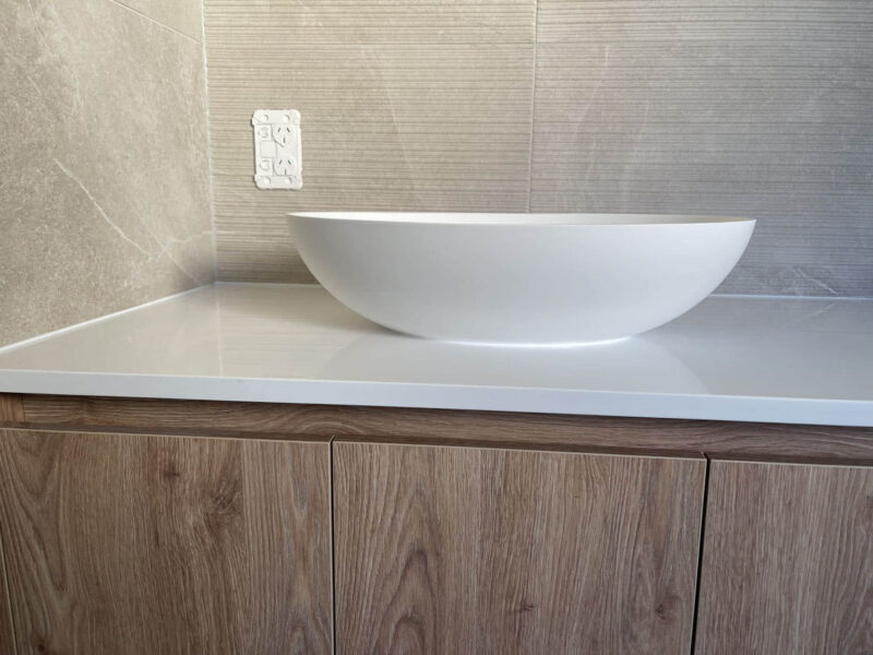 Custom bathroom vanity with white basin and wood cabinets.