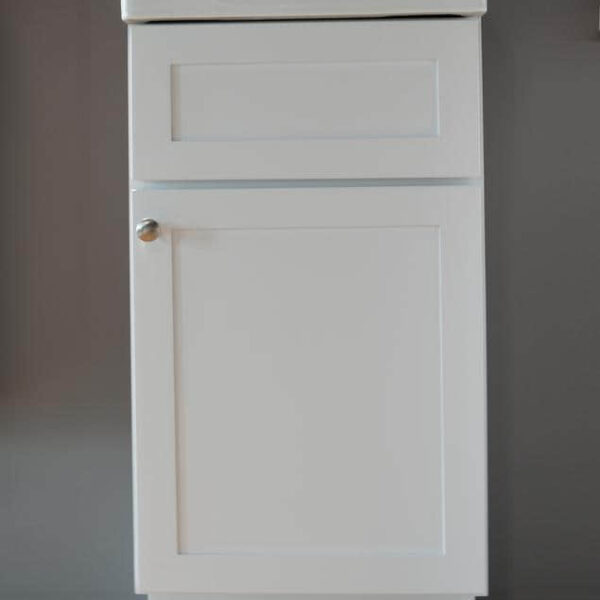 White kitchen cabinet with a single door and silver knob.