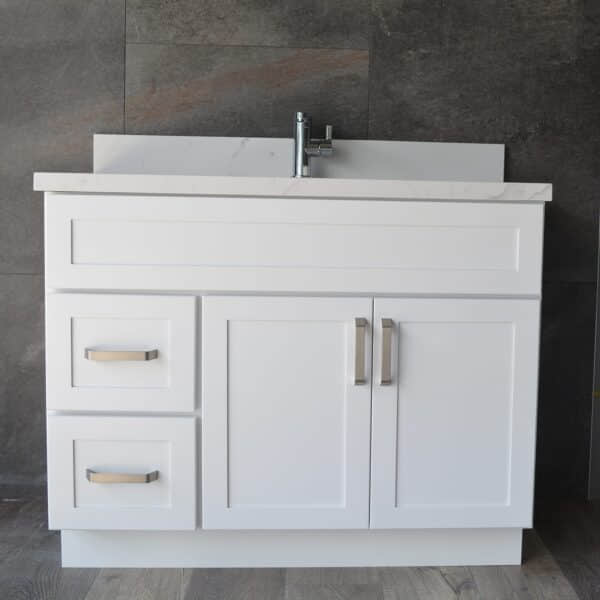 DSC_0194.jpg White bathroom vanity with drawers and sink against dark tiled wall.