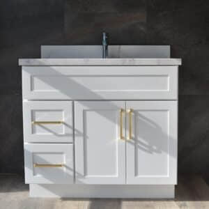 White bathroom vanity with gold handles and marble countertop.