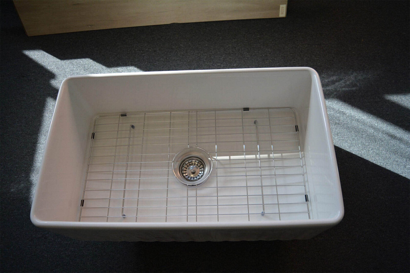 White kitchen sink with metal grid and drain.