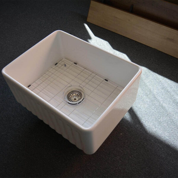 A white ceramic kitchen sink on a dark carpeted floor.