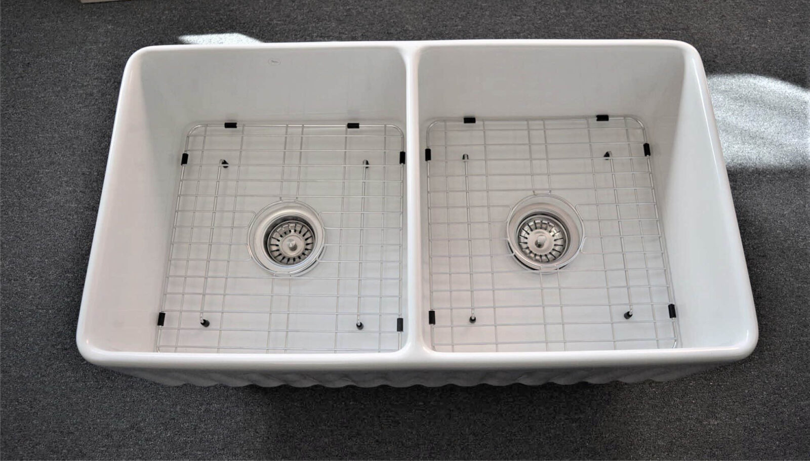 Double kitchen sink with metal grids and drains.