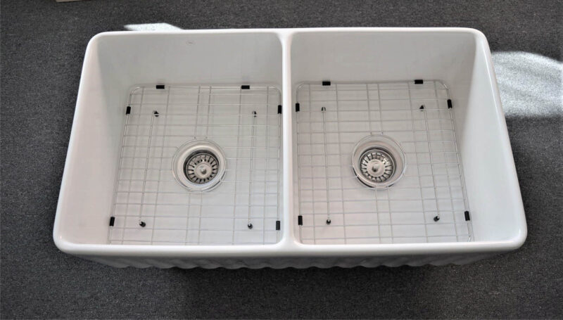 Double kitchen sink with metal grids and drains.