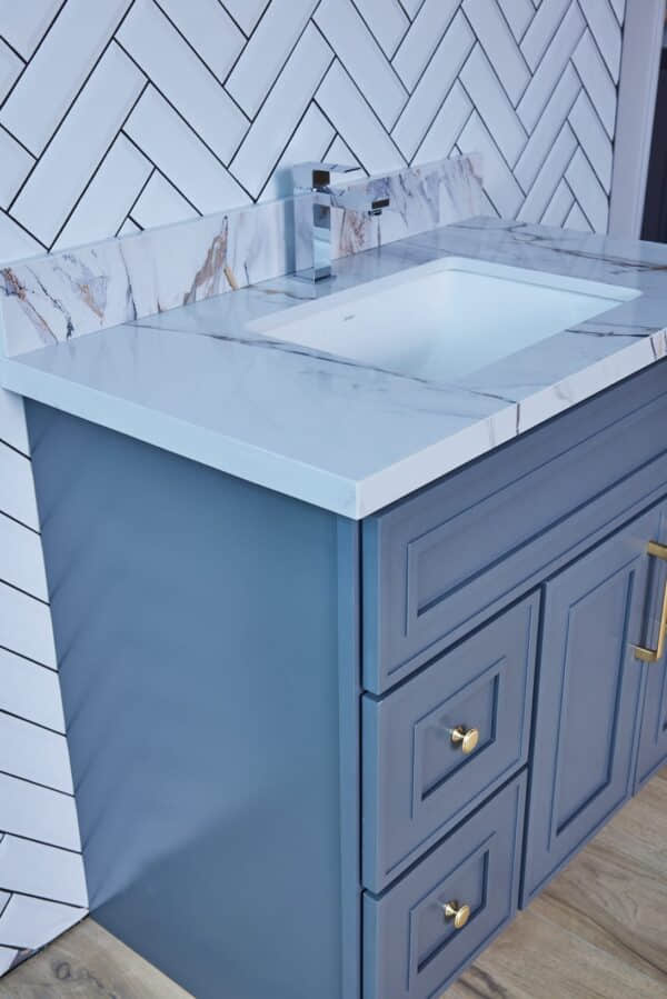 Blue bathroom vanity with marble countertop and modern faucet.