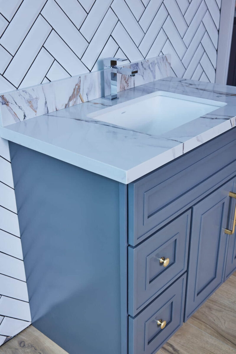 Blue bathroom vanity with marble countertop and modern faucet.