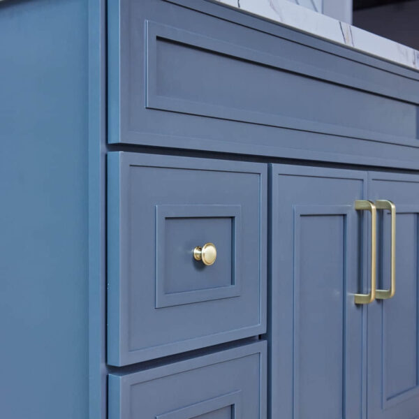 Blue kitchen cabinet with gold handles and marble countertop.