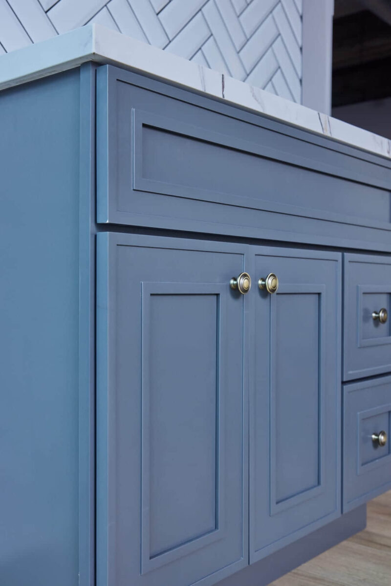 Blue kitchen cabinet with brass knobs.