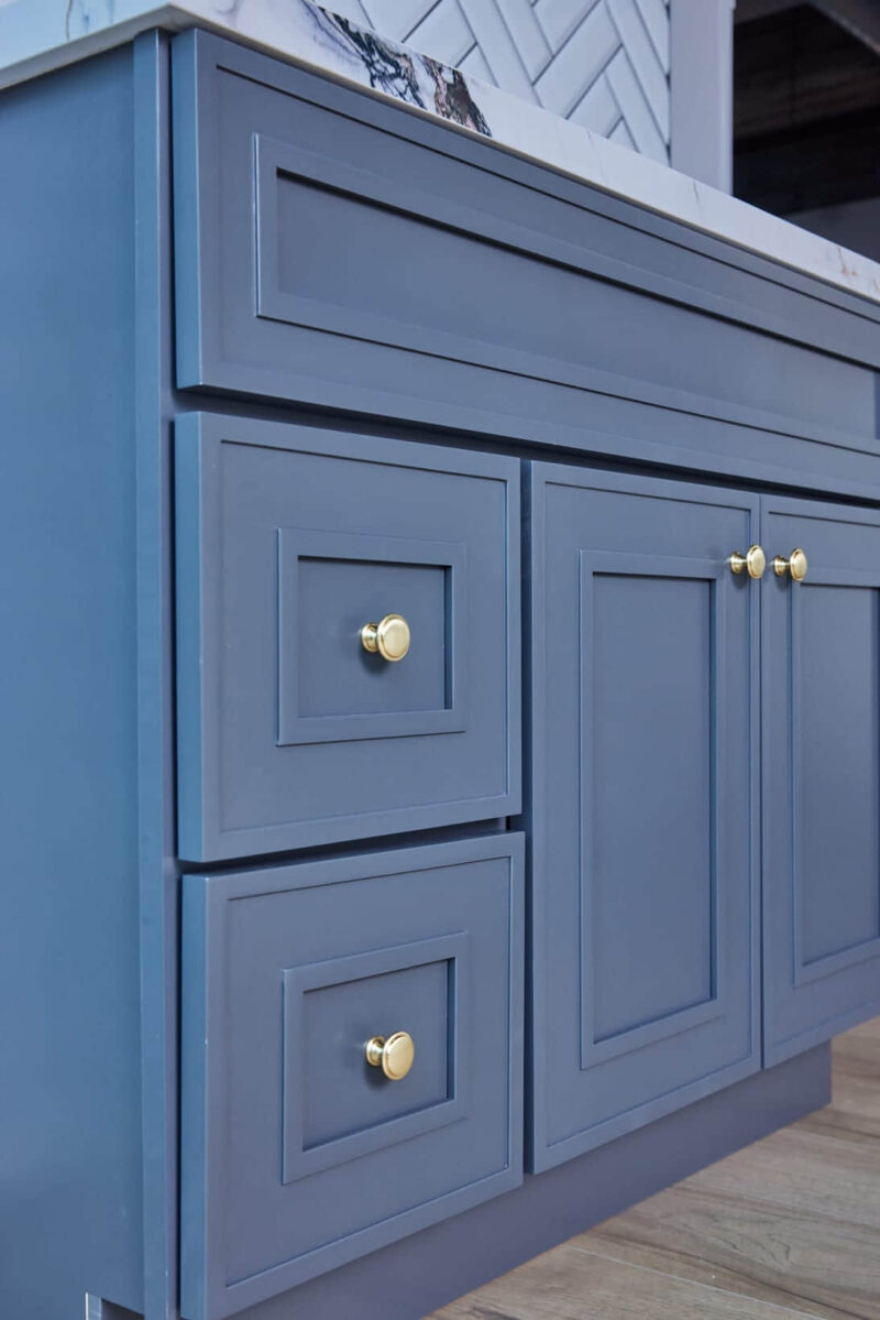 Blue kitchen cabinets with gold knobs.