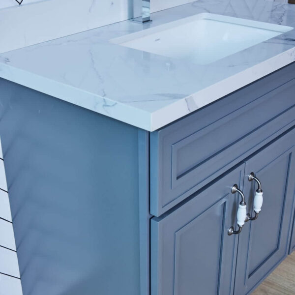 Blue bathroom vanity with marble countertop and silver handles.