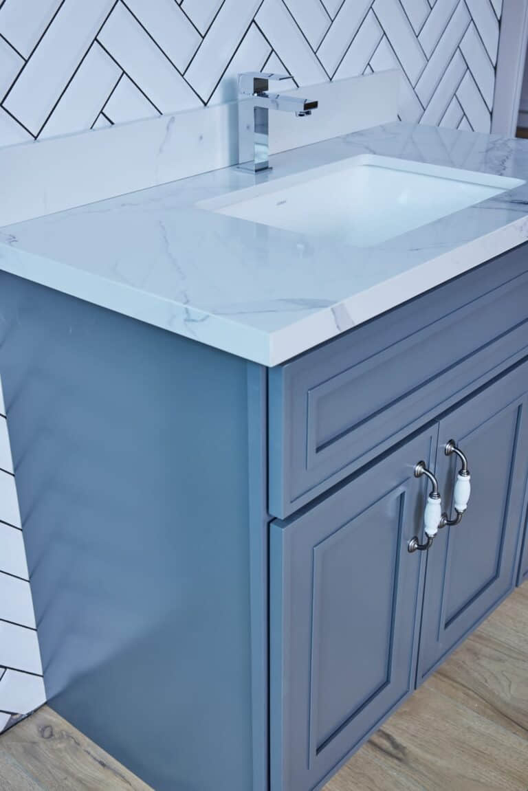 Blue bathroom vanity with marble countertop and silver handles.