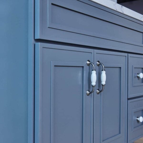 Blue kitchen cabinet with white handles and marble countertop.
