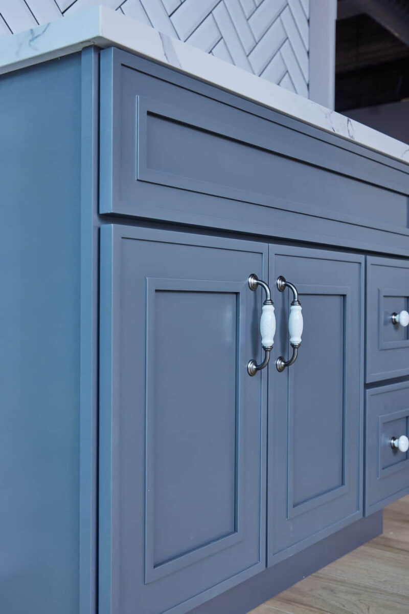 Blue kitchen cabinet with white handles and marble countertop.