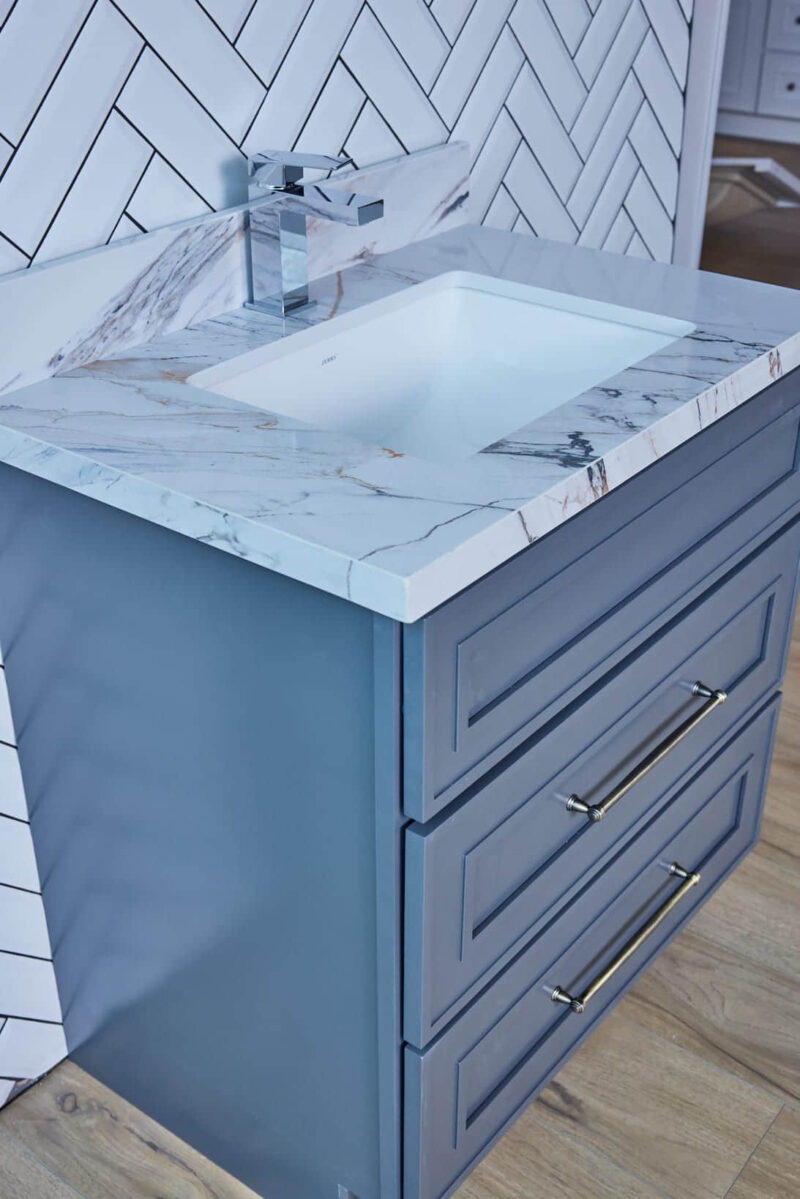Blue bathroom vanity with marble countertop and modern faucet.
