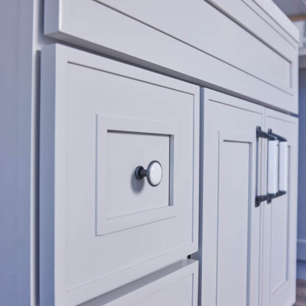White kitchen cabinets with modern handles and a marble countertop.