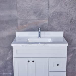 White bathroom vanity with marble countertop and gray tiled wall background.