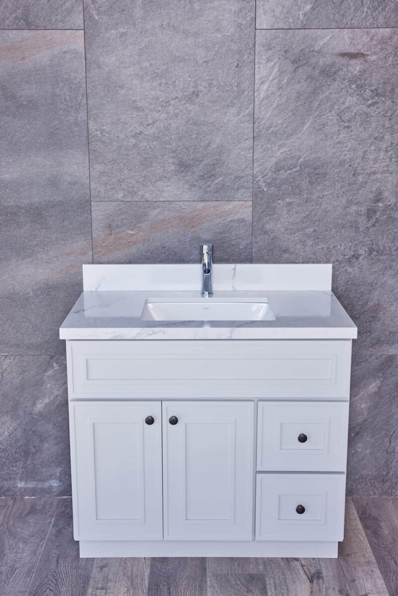 White bathroom vanity with marble countertop and gray tiled wall background.
