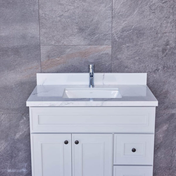 White bathroom vanity with marble countertop and gray tiled wall background.